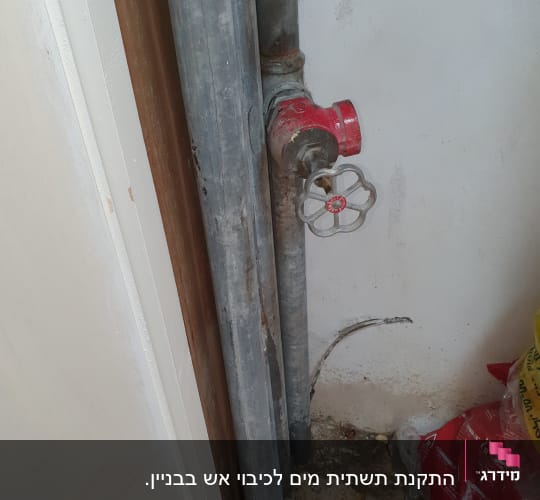 צינורות מתכת עם ברז אדום על קיר